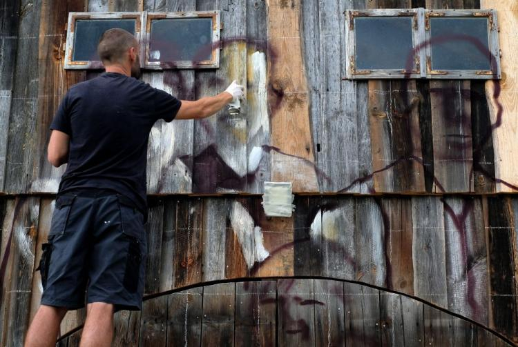  Arkadiusz Andrejkow wykonuje na starych zabudowaniach mural, w ramach swojego projektu "Cichy Memoriał" . Fot. PAP/D. Delmanowicz