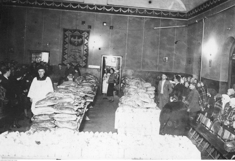 12 1939. Starachowice. Fragment spotkania świątecznego. Na stołach widoczne paczki żywnościowe przygotowane dla rodzin bezrobotnych. Źródło: NAC