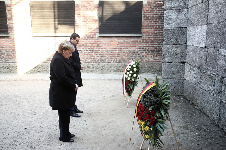 Kanclerz Niemiec Angela Merkel (L) oraz premier Mateusz Morawiecki (P) składają kwiaty przy Ścianie Straceń na terenie byłego niemieckiego nazistowskiego obozu zagłady Auschwitz. 06.12.2019. Fot. PAP/Łukasz Gągulski