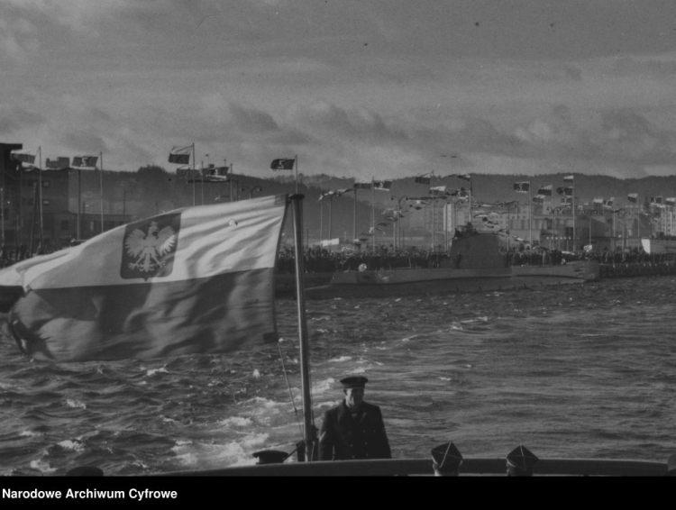 Powitanie okrętu podwodnego ORP "Orzeł" w porcie w Gdyni: ORP "Orzeł" przepływa obok nadbrzeża, przy którym witają go wiwatujące tłumy. Źródło: NAC
