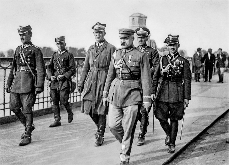 Zamach majowy. 12 maja 1926, Józef Piłsudski przed spotkaniem z prezydentem RP Stanisławem Wojciechowskim na moście Poniatowskiego. Od lewej: Kazimierz Stamirowski, Marian Żebrowski, Gustaw Orlicz-Dreszer, Józef Piłsudski, Władysław Jaroszewicz i Michał Galiński. Na oryginalnej fotografii sprzed kadrowania z prawej widoczny także st. wachm. Walenty Wójcik. Fot. Marian Fuks (1884-1935), Public domain, via Wikimedia Commons