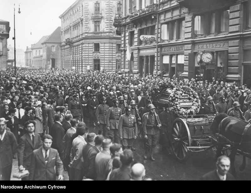 Kondukt żałobny na ul. Wierzbowej w Warszawie. Z prawej widoczne szyld zakładu zegarmistrzowskiego "L. M. Lilpop" . Fot. NAC