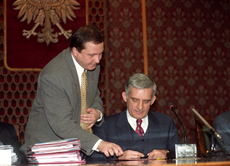 Premier Jerzy Buzek podpisuje dokumenty o przystąpieniu Polski do NATO, obok stoi szef kancelarii premiera Wiesław Walendziak, fot. PAP/Radek Pietruszka