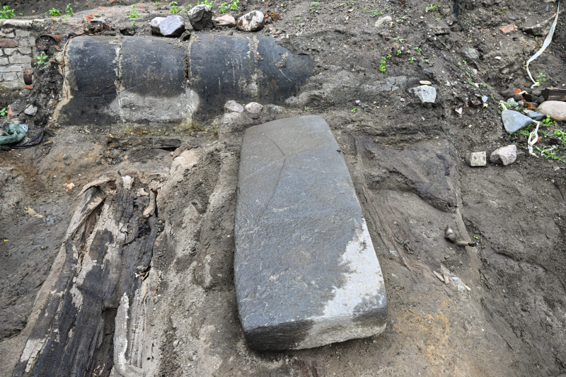 Gdańsk, 7.07.2026 r. Płyta nagrobna z reliefem krzyża łacińskiego z XIII wieku w Gdańsku. Archeolodzy natrafili na artefakt w trakcie wykopalisk prowadzonych u zbiegu ulic Grodzkiej i Sukienniczej. Fot. PAP/Marcin Gadomski