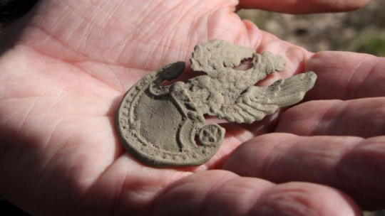 Orzełek z wojskowej czapki znaleziony w lesie koło Starego Grodkowa podczas poszukiwań szczątków żołnierzy z oddziału "Bartka" (Henryka Flamego) zamordowanych przez UB pod koniec lata 1946 r. Fot. PAP/K. Świderski