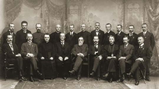 Stoją: Kazimieras Bizauskas, Jonas Vailokaitis, Donatas Malinauskas, kun. Vladas Mironas, Mykolas Biržiška, kun. Alfonsas Petrulis, Saliamonas Banaitis, Petras Klimas, Aleksandras Stulginskis, Jokūbas Šernas, and Pranas Dovydaitis. Siedzą: Jonas Vileišis, Dr. Jurgis Šaulys, kun. Justinas Staugaitis, Stanislovas Narutavičius, Dr. Jonas Basanavičius, Antanas Smetona, kan. Kazimieras Steponas Šaulys, Steponas Kairys, and Jonas Smilgevičius. Źródło: Wikipedia Commons