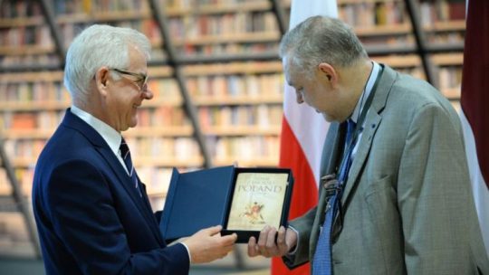 Jacek Czaputowicz przekazuje dyrektorowi Łotewskiej Biblioteki Narodowej Andrisowi Vilksowi książkę Adama Zamoyskiego 'Poland. A History'. Fot. PAP/J. Turczyk 