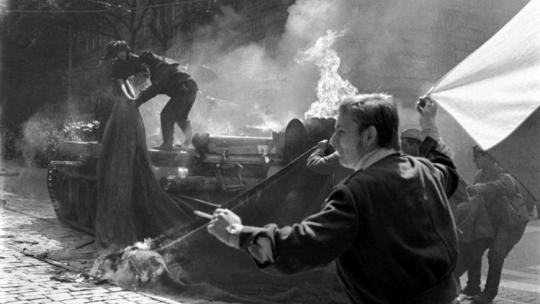 Młodzi mieszkańcy Pragi z narodowymi flagami przy palącym się 21 sierpnia 1968 r. radzieckim czołgu. Fot. PAP/CTK