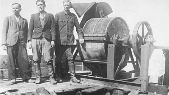 Grupa więźniów Sonderkommando 1005 przy młynie do mielenia kości. Źródło: Wikimedia Commons