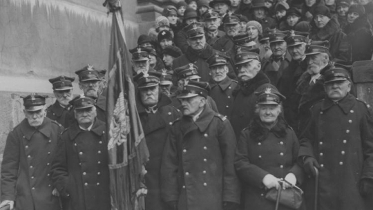 67 rocznica wybuchu Powstania Styczniowego. Grupa weteranów opuszcza kościół św. Krzyża po nabożeństwie. Widoczni m.in: Antoni (stoi za kobietą weteranem) i Arkadiusz (stoi po lewej ręce kobiety weterana) Strzałeccy, Maria Bentkowska. Źródło NAC