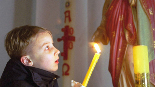 Mińsk, Białoruś, 26.12.2000. Chłopiec trzyma świecę w czasie mszy wigilijnej dla dzieci w kościele rzymsko-katolickim w Mińsku w niedzielę, 24 bm. Fot. PAP/EPA/W. Draczew