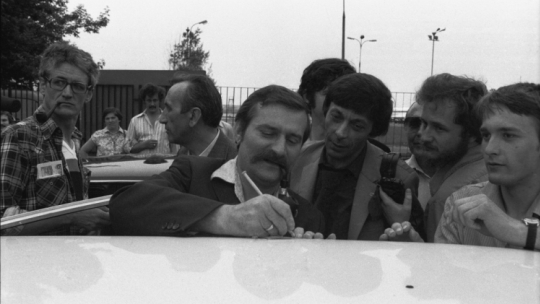 Warszawa, 1981-06-08. Lech Wałęsa wraca z dorocznej konferencji Międzynarodowej Organizacji Pracy w Genewie, 5 czerwca 1981 r. wygłosił entuzjastycznie przyjęte przemówienie, relacjonowane przez wszystkie telewizje zachodnioeuropejskie. Nz. przed halą przylotów na Okęciu Lech Wałęsa (C) daje autograf chłopcu, kartkę położył na dachu samochodu. Z lewej dziennikarze Tygodnika Solidarność: Krzysztof Wyszkowski (L) i Tadeusz Mazowiecki (2L) - red. naczelny pisma. Fot. PAP/CAF/A. Rybczyński