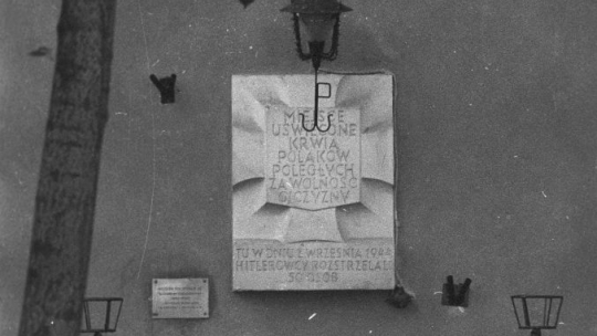 Tablica pamiątkowa Tchorka na ścianie kamienicy przy placu Zamkowym 15/19 upamiętnia pacjentów powstańczych szpitali oraz cztery towarzyszące im sanitariuszki, których Niemcy wzięli do niewoli po upadku Starego Miasta i rozstrzelali na pl. Zamkowym. 1973 r. Fot. PAP/C. Niedenthal