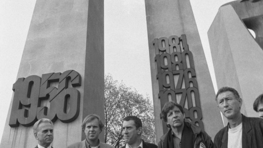 Poznań 26.04.1992. Amerykański aktor i producent filmowy Robert De Niro (C) przy pomniku Poznańskiego Czerwca 1956 (tzw. Poznańskie Krzyże) na placu Mickiewicza podczas swojej wizyty w Poznaniu; widoczni są także: wiceprezydent Poznania Ryszard Olszewski (L), biznesmen, kolekcjoner dzieł sztuki i były tenisista Wojciech Fibak (2L) oraz amerykański aktor, także scenarzysta i reżyser filmowy Barry Primus (2P). Fot. PAP/R. Królak