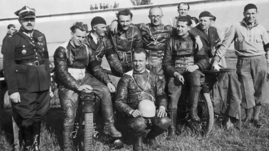 Mecz motocyklowy Warszawa - Wiedeń rozgrywany na Stadionie Wojska Polskiego w Warszawie w czerwcu 1935 r. Fotografia grupowa uczestników zawodów. Widoczni m.in.: major Gruszka (stoi). Siedzą od lewej: Walz, Edward Langer, Ilchman, Jóżef Docha, Riedl, Frankowski (klęczy). Fot. Narodowe Archiwum Cyfrowe