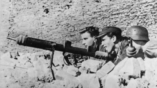 Powstańcy warszawscy na stanowisku ogniowym, uzbrojeni w granatnik przeciwpancerny typu PIAT, 1944 r. Fot. AIPN