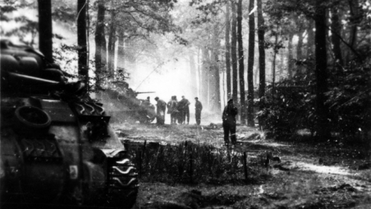 1 Dywizja Pancerna w Holandii: grupa żołnierzy w lesie. na pierwszym planie czołg "Sherman". Fot. NAC