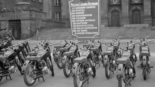 Maj 1955 r. Motocykle przeznaczone dla przodowników i racjonalizatorów hutnictwa wystawione przed Urzędem Wojewódzkim w Katowicach. Z tyłu obwieszczenie co jeszcze dostaną. Fot. PAP/CAF/Kazimierz Seko