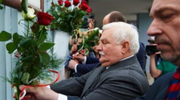 Lech Wałęsa w towarzystwie min. Bogdana Zdrojewskiego przypina kwiaty do bramy Stoczni Gdańskiej Fot. PAP/A.Warżawa