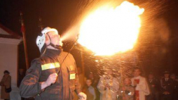 Strażacy "bziukają" czyli wydmuchują z ust fontanny nafty, która zapala się od pochodni. Fot. PAP/P. Polak
