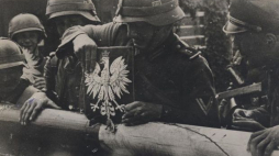 Żołnierze niemieccy zrywają godło Polski ze szlabanu granicznego. Przejście graniczne w Kolibkach, 01.09.1939. Źródło: CAW