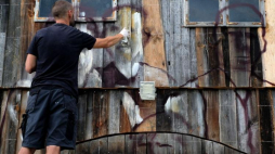  Arkadiusz Andrejkow wykonuje na starych zabudowaniach mural, w ramach swojego projektu "Cichy Memoriał" . Fot. PAP/D. Delmanowicz