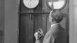 Pracownik obserwatorium stojący przy zegarze, który jest połączony kablem podziemnym z zegarem regulacyjnym w Ministerstwie Komunikacji. - 1932 r. Źródło: NAC