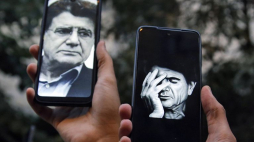 Mohammad Reza Szadżarian na ekranach telefonów osób zgromadzonych przed szpitalem, w którym zmarł artysta. Fot. PAP/EPA