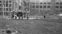 Delegacja ZWM biegnie pod krzyż Traugutta złożyć wieniec. W tle zniszczony w czasie wojny gmach Polskiej Wytwórni Papierów Wartościowych przy ul. Sanguszki 1. 1948 r. Fot. PAP/CAF/W. Kondracki