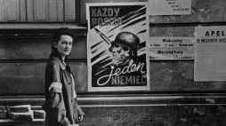 Łączniczka przy plakacie autorstwa Henryka Chmielewskiego „Każdy pocisk jeden Niemiec”. Warszawa, sierpień 1944 r. Autor: Eugeniusz Lokajski, fot. z zasobu IPN