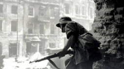 Powstaniec warszawski obserwuje Krakowskie Przedmieście przez wyburzoną ścianę kościoła św. Krzyża w kierunku ul. Kopernika. Fot. Eugeniusz Haneman. Źródło: Wikimedia Commons