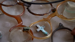 Krzyżyk i fragmenty okularów znalezione na terenie, na którym działał obóz koncentracyjny KL Stutthof. Fot. PAP/Adam Warżawa 