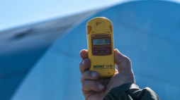 Dozymetr do pomiaru promieniowania na tle kopuły nad zniszczonym reaktorem elektrowni jądrowej w Czarnobylu. Fot. PAP/Vladyslav Musiienko