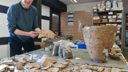 Archeolog Paweł Kaźmierczak prezentuje opracowywane fragmenty naczyń z okresu kultury łużyckiej. Fot. PAP/P. Kaźmierczak