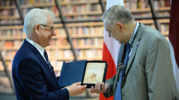 Jacek Czaputowicz przekazuje dyrektorowi Łotewskiej Biblioteki Narodowej Andrisowi Vilksowi książkę Adama Zamoyskiego 'Poland. A History'. Fot. PAP/J. Turczyk 