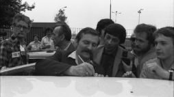 Warszawa, 1981-06-08. Lech Wałęsa wraca z dorocznej konferencji Międzynarodowej Organizacji Pracy w Genewie, 5 czerwca 1981 r. wygłosił entuzjastycznie przyjęte przemówienie, relacjonowane przez wszystkie telewizje zachodnioeuropejskie. Nz. przed halą przylotów na Okęciu Lech Wałęsa (C) daje autograf chłopcu, kartkę położył na dachu samochodu. Z lewej dziennikarze Tygodnika Solidarność: Krzysztof Wyszkowski (L) i Tadeusz Mazowiecki (2L) - red. naczelny pisma. Fot. PAP/CAF/A. Rybczyński