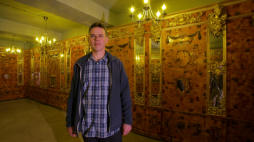 Bartłomiej Plebańczyk, inicjator poszukiwań i przedstawiciel muzeum, na tle repliki Bursztynowej Komnaty. Fot. PAP/T. Waszczuk