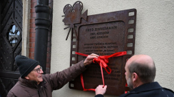 Rzeszów, 11.12.2023. Prezydent Rzeszowa Konrad Fijołek (P) i syn Freda Zinnemanna Tim Zinnemann (L) podczas odsłonięcia tablicy pamiątkowej Freda Zinnemanna, na fasadzie kamienicy przy ul. Rynek 3. Fot. PAP/D. Delmanowicz