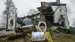 Olena Panina pokazuje, jak wyglądał kościół Narodzenia Najświętszej Maryi Panny we wsi Wiazówka w obwodzie żytomierskim na Ukrainie przed rosyjskim bombardowaniem w marcu 2022 r. XIX-wieczny drewniany kościół Narodzenia Najświętszej Maryi Panny to zabytek architektury o znaczeniu narodowym. Fot. PAP/V. Musiienko