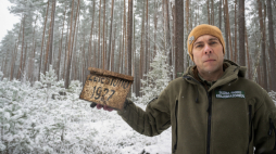 Pracownik WPK, odpowiedzialny za prowadzenie badań archeologicznych Mateusz Sosnowski z tabliczką Lasów Państwowych potwierdzającą rok nasadzenia drzew rosnących w obrębie odkrytego obozu partyzantów Armii Krajowej na terenie Wdeckiego Parku Krajobrazowego w Lipinkach, 11 bm. Obozowisko oddziału "Świerki 101" znajduje się przy północnej granicy województwa nad rzeką Sobińska Struga. PAP/Tytus Żmijewski