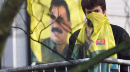 Jeden z Kurdów, którzy wdarli się do rezydencji ambasadora Grecji w Hadze biorąc dwie kobiety i dziecko za zakładników, stoi na balkonie budynku z twarzą ukrytą w chuście z podobizną kurdyjskiego przywódcy Ocalana, 1999 r. PAP/EPA/ Jasper Juinen