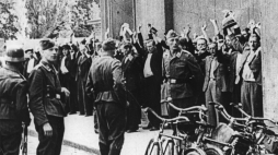 Niemieccy żołnierze przetrzymują ludność cywilną - ofiary ulicznej łapanki. Fot. PAP/CAF