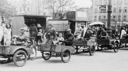 Reprodukcja zdjęcia Stefana Bałuka: Postój riksz na placu Żelaznej Bramy w Warszawie, lipiec 1944 r. Widok na południową część placu. W głębi widoczne kamienice u wylotu ulicy Granicznej: od prawej stoi budynek pl. Żelaznej Bramy 3 (róg Graniczna 17), potem (zasłonięty) wylot Granicznej i zburzony dom nr 5, po lewej budynek pl. Żelaznej Bramy 3. Fot. PAP/Reprodukcja