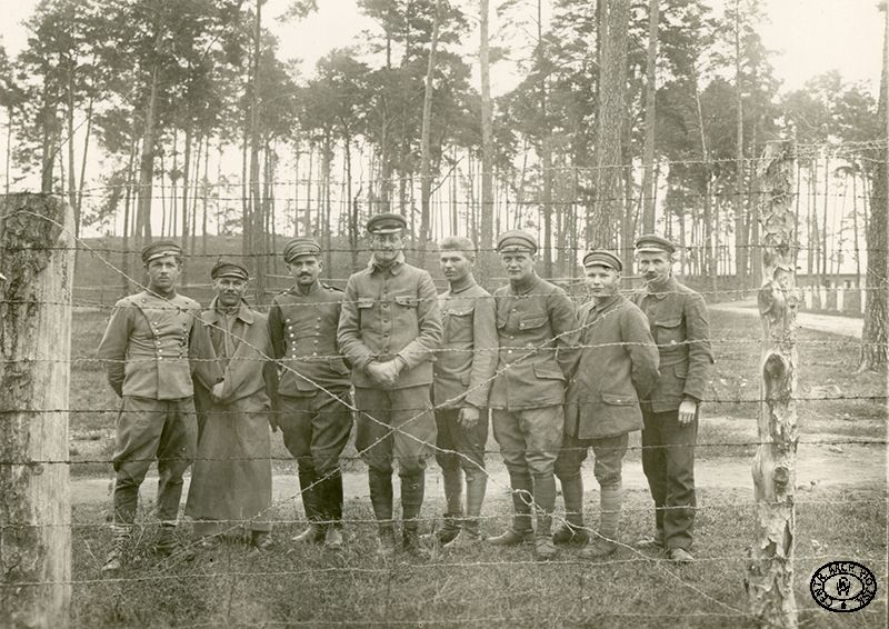 Oficerowie legionowi za ogrodzeniem obozowym. Czwarty od lewej mjr Stanisław Burchardt ps. „Bukacki”. Beniaminów. Wiosna 1918 r. Źródło: CAW