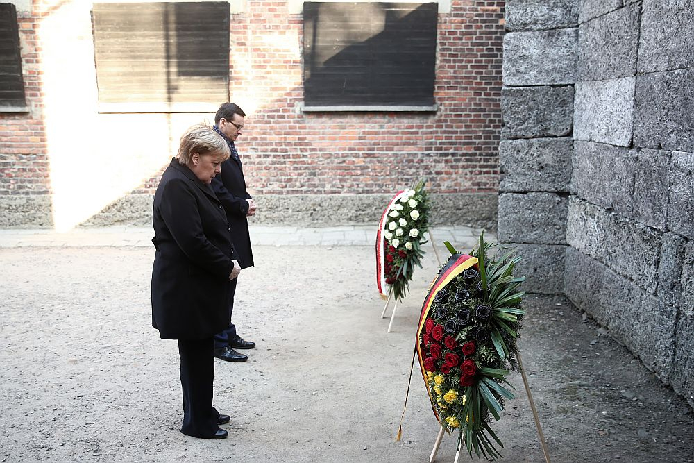 Kanclerz Niemiec Angela Merkel (L) oraz premier Mateusz Morawiecki (P) składają kwiaty przy Ścianie Straceń na terenie byłego niemieckiego nazistowskiego obozu zagłady Auschwitz. Fot. PAP/Ł. Gągulski