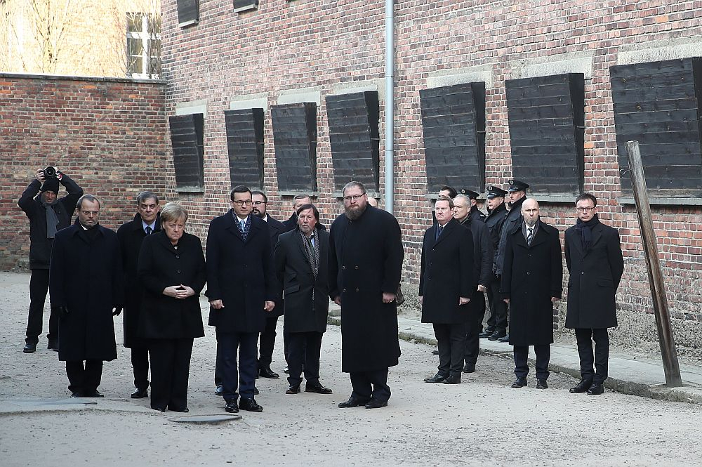 Kanclerz Niemiec Angela Merkel (4L) oraz premier Mateusz Morawiecki (5L) i dyrektor Państwowego Muzeum Auschwitz-Birkenau Piotr Cywiński (8L) składają kwiaty przy Ścianie Straceń na terenie byłego niemieckiego nazistowskiego obozu zagłady Auschwitz. Fot. PAP/Ł. Gągulski