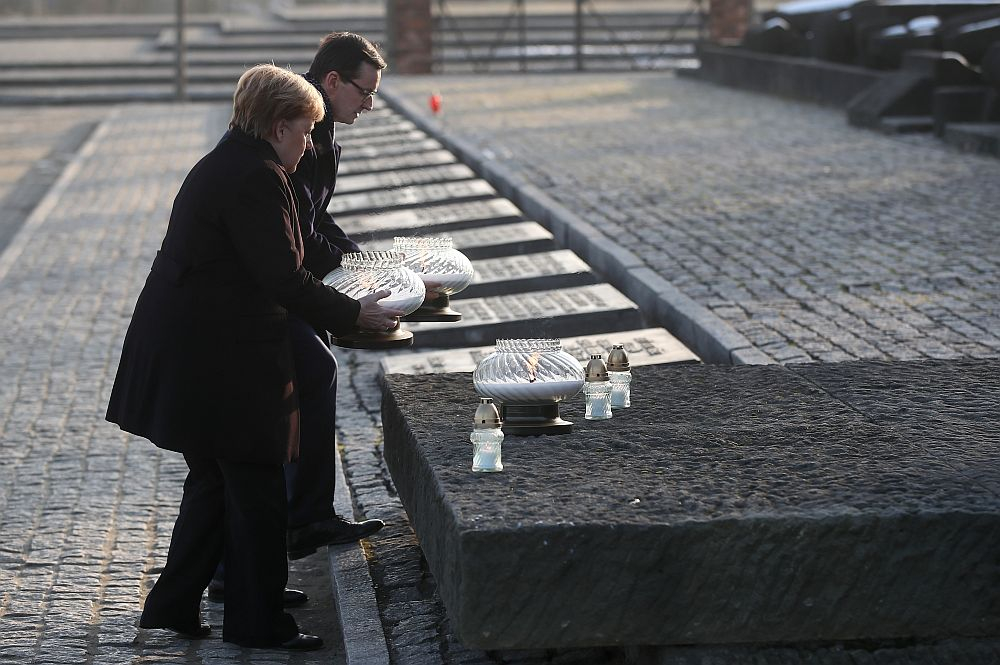 Kanclerz Niemiec Angela Merkel (L) i premier Mateusz Morawiecki (P) zapalają znicze przy Międzynarodowym Pomniku Ofiar Obozu na terenie byłego niemieckiego nazistowskiego obozu zagłady Auschwitz II-Birkenau. Fot. PAP/Ł. Gągulski