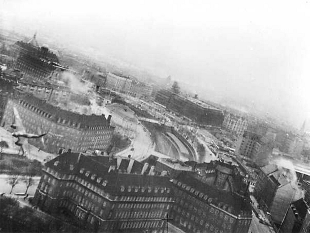 21 marca 1945, Kopenhaga. Jeden z 20 samolotów Mosquito przelatuje tuż nad dachami budynków w trakcie  operacji „Carthage” – nalotu na siedzibę gestapo, gmach Shellhuset przy Kampmannsgade. źródło: domena publiczna
