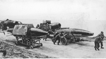 Bateria bomb latających V-1 na polu startowym. Widoczne cztery pociski na wózkach transportowych przesuwane przez żołnierzy. Fot. NAC