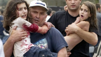 Mężczyźni niosą dzieci, które uciekły z budynku szkoły tuż po rozpoczęciu akcji uwalniania zakładników w Biesłanie. Fot. NTV/PAP/EPA/Yuri Kochetkov